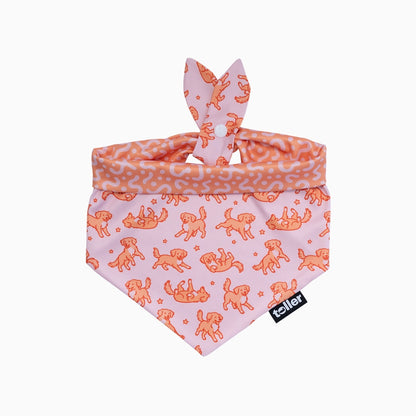 Dog bandana with dog pattern on pink background, featuring a brand label.