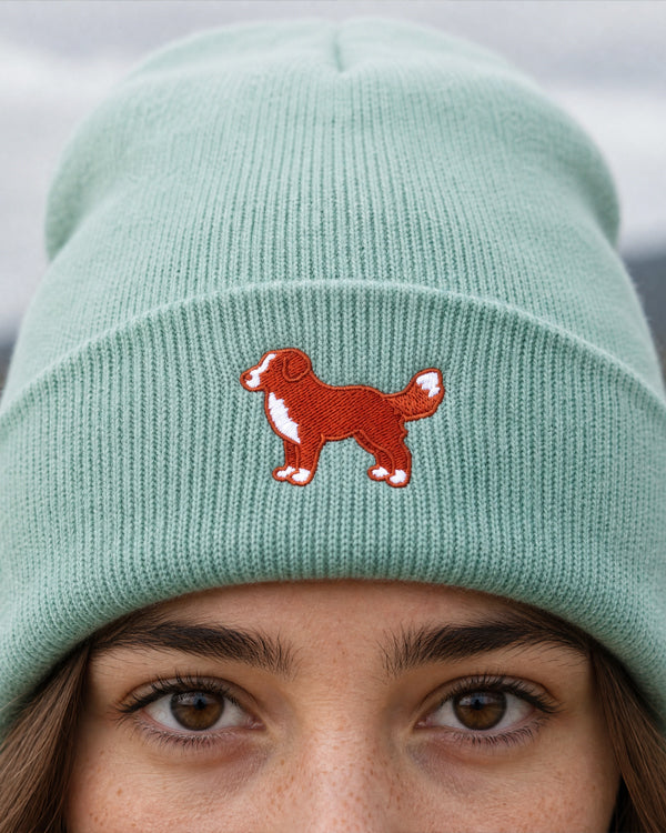 Light green beanie with a red dog illustration worn by a person.