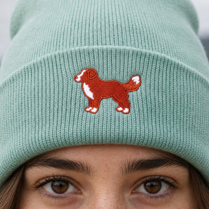 Green beanie with a red dog illustration worn by a person.