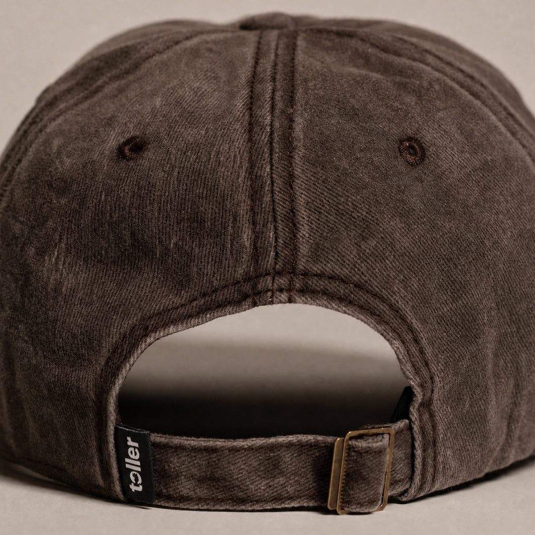 Brown baseball cap with 'teller' brand label on a beige background