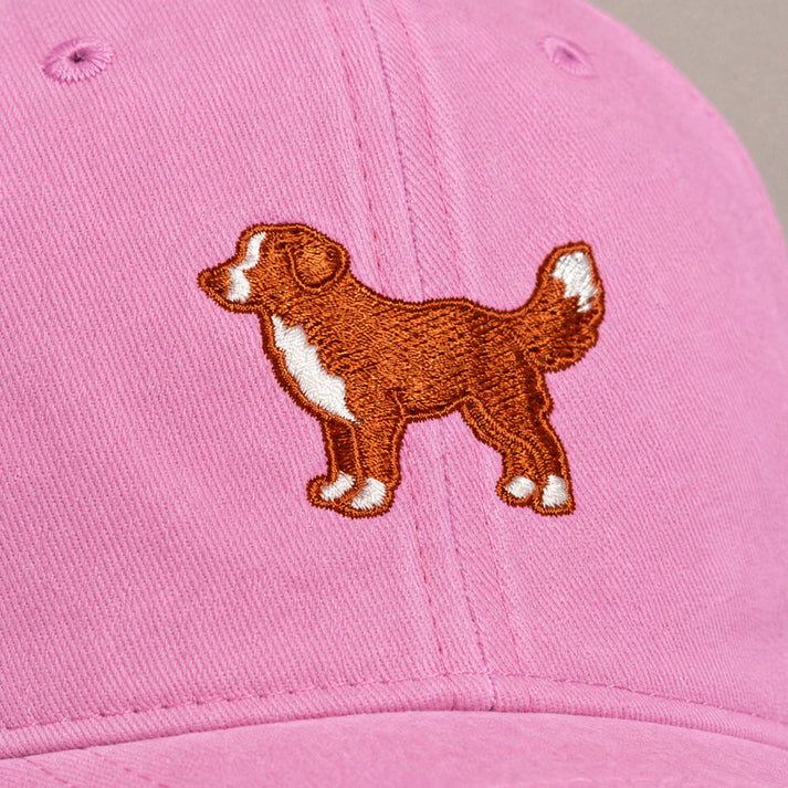 Pink cap with a brown dog illustration on a gray background