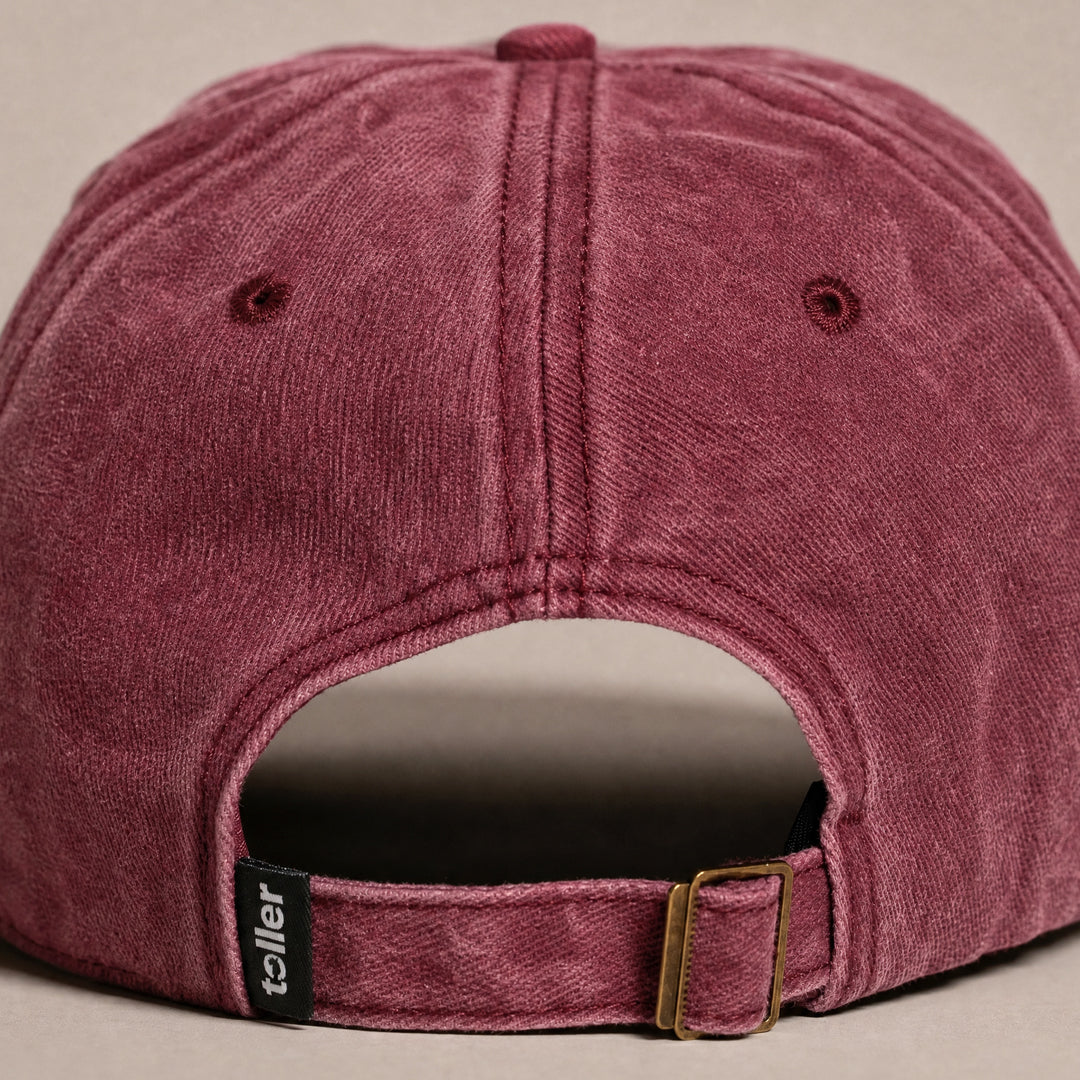 Maroon cap with a visible brand logo on a beige background