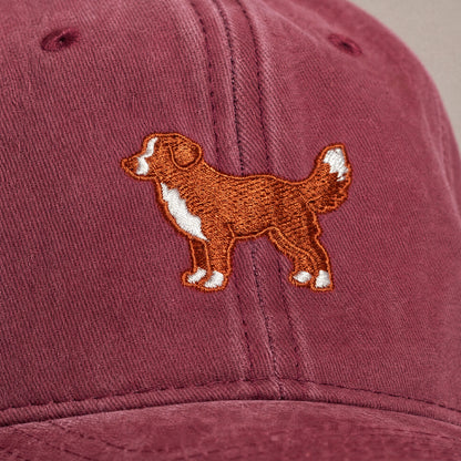 Maroon cap with embroidered dog design on a beige background