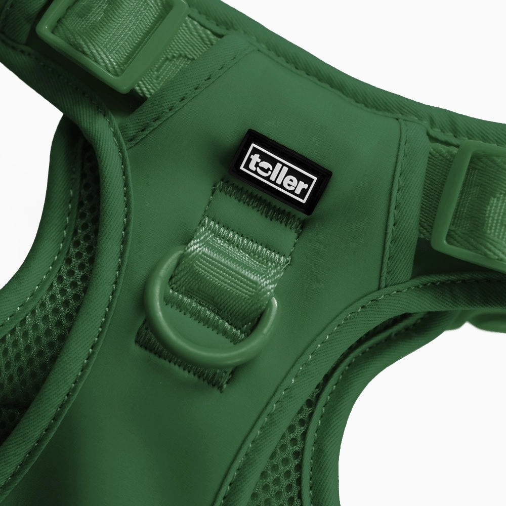 Green dog harness with 'toller' brand label on a white background