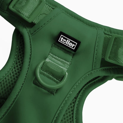 Green dog harness with 'toller' brand label on a white background
