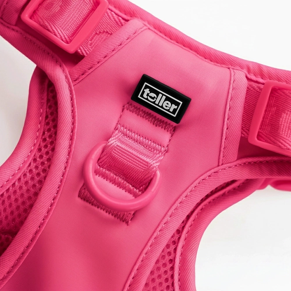 Close-up of a pink dog harness with a visible brand label on a white background